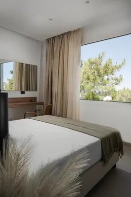 a bedroom with a large bed and a large window at Theros Luxury Apartment in Archangelos
