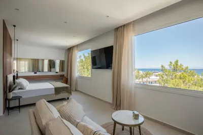 a bedroom with a bed and a large window at Theros Luxury Apartment in Archangelos