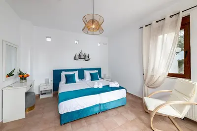a bedroom with a blue and white bed and a chair at Evilion Villa in Gennadi