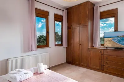 a bedroom with a bed and a tv and windows at Evilion Villa in Gennadi