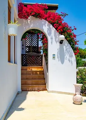 an archway with red flowers on a building with stairs at Evilion Villa in Gennadi