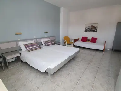 a bedroom with a large white bed and a couch at Stonegarden Studios in Faliraki