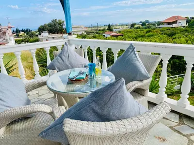a glass table on a balcony with pillows at The Citrus House in Kalavárda