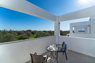 a balcony with a table and chairs and a large window at Domus Oliva Villas in Haraki
