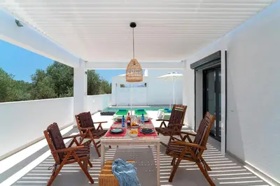 a patio with a table and chairs and a pool at Domus Oliva Villas in Haraki