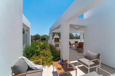a patio with two chairs and a table at Domus Oliva Villas in Haraki