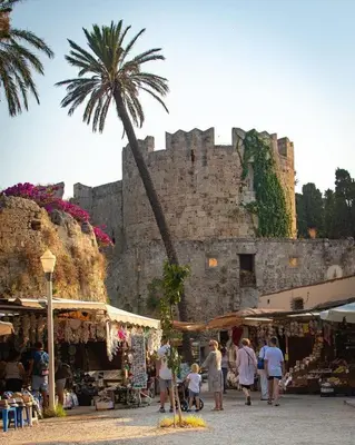 a group of people walking around a market in front of a castle at City Center Elite Suite in Rhodes Town