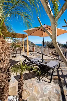 a table and chairs and an umbrella on a patio at Sea Rock Villa Rodos in Archangelos