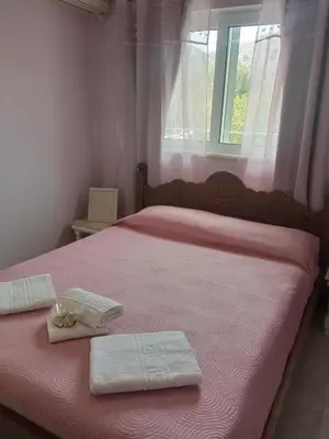 a bedroom with a pink bed with two towels and a window at Marilen in Livadia