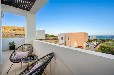 a balcony with two chairs and a view of the ocean at Adore Lindos Villa in Líndos