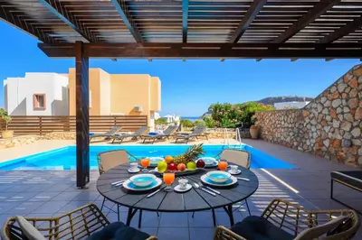 a patio with a table and chairs next to a pool at Adore Lindos Villa in Líndos