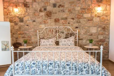 a white bed in a room with a stone wall at Roccia di Isidoro in Áyios Isídhoros