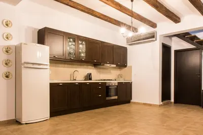 a kitchen with wooden cabinets and a white refrigerator at Roccia di Isidoro in Áyios Isídhoros