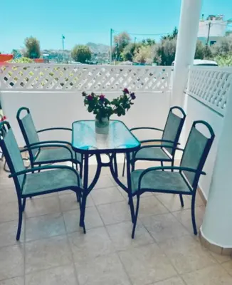 a table with four chairs and a vase with flowers on it at Thalassia Avra Stegna Beach in Archangelos