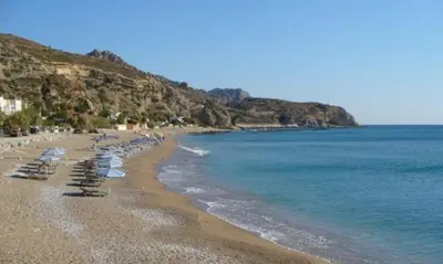 a beach with chairs and umbrellas and the ocean at Thalassia Avra Stegna Beach in Archangelos