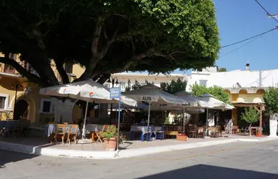 an outdoor cafe with umbrellas and tables and chairs at Lotza Traditional House Salakos in Sálakos