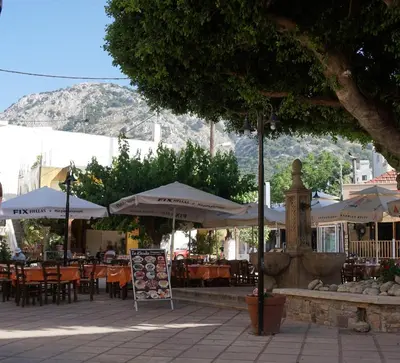 an outdoor cafe with tables and umbrellas and chairs at Lotza Traditional House Salakos in Sálakos