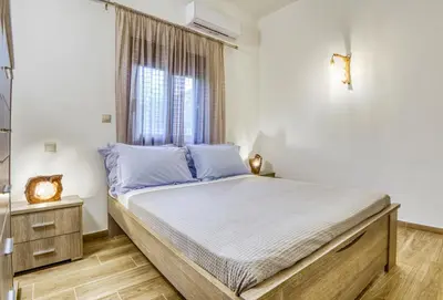 a bedroom with a bed with blue pillows and a window at Villa Crypty in Soroni