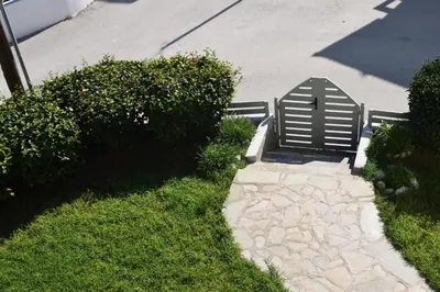 a bench sitting on the grass next to a sidewalk at Lefteris Apartments in Ialysos Rhodes in Ialyssos
