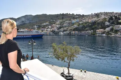 a woman looking out over a body of water with a ship at Cavo apartment in Symi