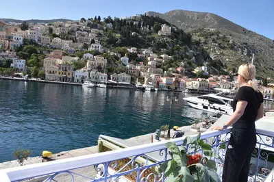 a woman standing on a balcony looking at a harbor at Cavo apartment in Symi