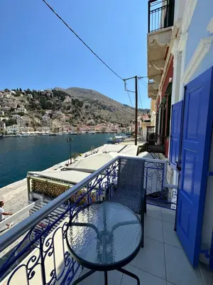 a balcony with a table and chairs on a building at Cavo apartment in Symi