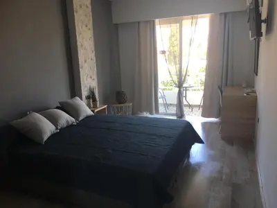 a bedroom with a blue bed and a large window at RHODIAN TREASURE Spiridione studio 1 in Faliraki