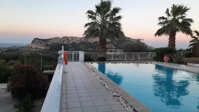 a swimming pool with palm trees and a mountain in the background at Villa Selene in Archangelos