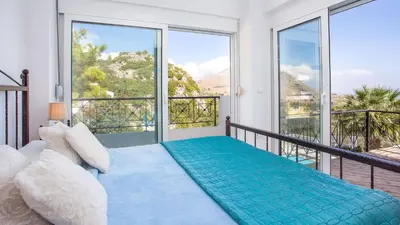 a bedroom with a bed and a balcony with large windows at Villa Selene in Archangelos