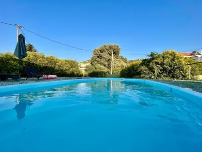 a large blue swimming pool with an umbrella at Masefa villa in Ialyssos