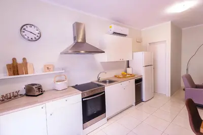 a kitchen with white cabinets and a clock on the wall at Masefa villa in Ialyssos