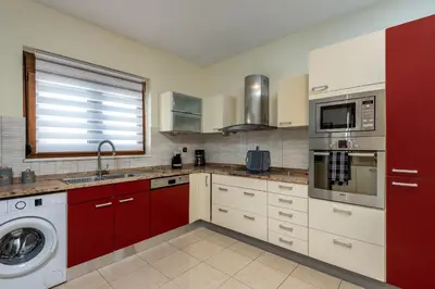 a kitchen with red cabinets and a washing machine at Aileen Villa in Koskinou