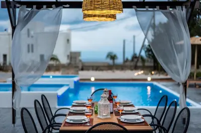 a table with chairs in front of a pool at Aileen Villa in Koskinou