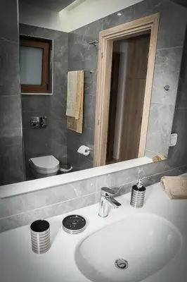 a bathroom with a sink and a toilet and a mirror at Seaside Luxury Apartments Kremasti in Kremasti