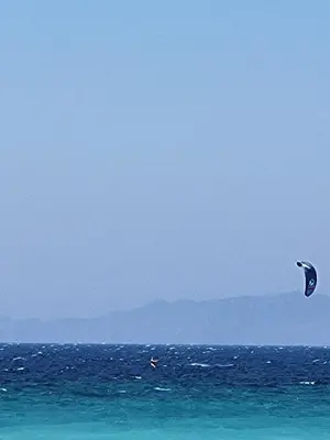 a person is flying a kite in the ocean at Seaside Luxury Apartments Kremasti in Kremasti