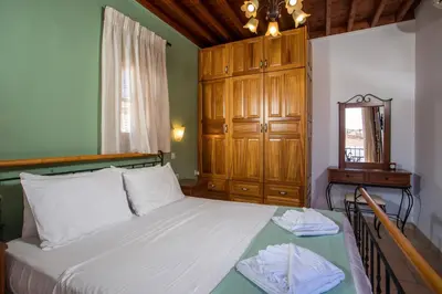 a bedroom with a bed with a wooden cabinet and a mirror at Villa Sakura in Líndos