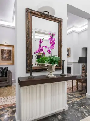 a mirror and a vase with purple flowers on a table at Arhondiko Apartment VS Rhodes Town in Rhodes Town