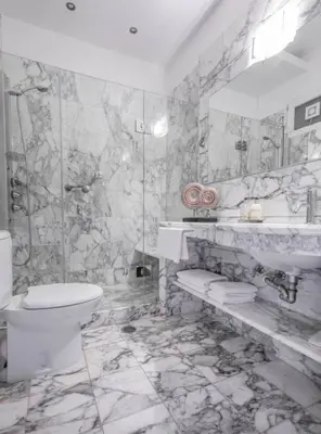 a marble bathroom with a toilet and a sink at Arhondiko Apartment VS Rhodes Town in Rhodes Town