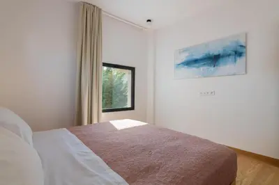 a white bedroom with a bed and a window at Nisi Living Concept in Ialyssos