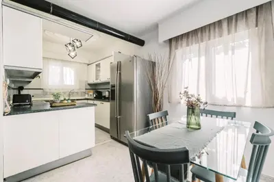 a kitchen with a table with chairs and a refrigerator at Bella Terra Villa Filerimos in Rhodes Town