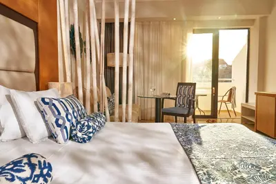 a bedroom with a bed with blue and white pillows at Lindos Bay Hotel in vlicha