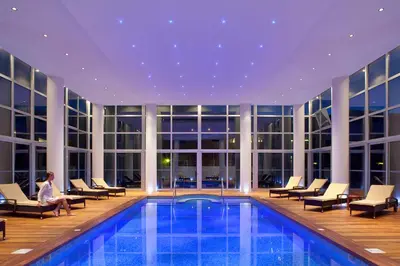 a hotel pool with chairs and a person sitting next to it at Lindos Bay Hotel in vlicha