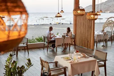 a man and woman sitting at a table in a restaurant at Lindos Bay Hotel in vlicha