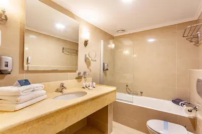 a bathroom with a sink and a tub and a toilet at Lindos Bay Hotel in vlicha