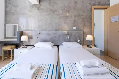 two beds in a room with two tables and two lamps at Mando Living -Faliraki in Faliraki