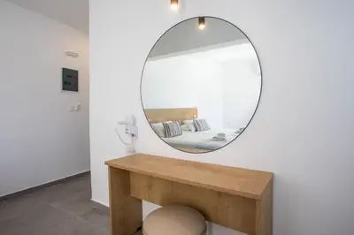 a mirror on a wall above a wooden table at Mando Living -Faliraki in Faliraki