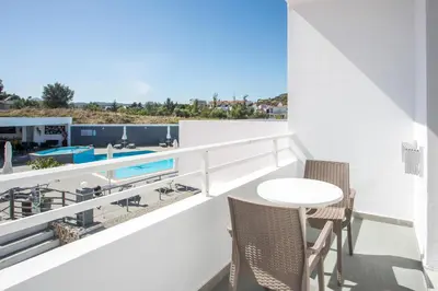 a balcony with a table and chairs and a pool at Mando Living -Faliraki in Faliraki