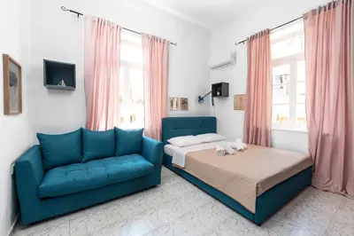 a bedroom with a bed and a blue couch at Palm Residence lll - Islander's Home Collection in Rhodes Town