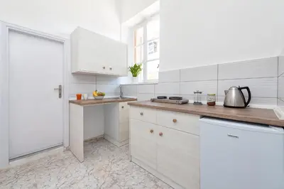 a white kitchen with white cabinets and a counter at Palm Residence lll - Islander's Home Collection in Rhodes Town