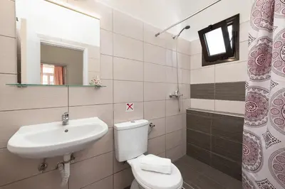 a bathroom with a sink and a toilet and a mirror at Palm Residence lll - Islander's Home Collection in Rhodes Town